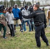 Flüchtlinge am Eurotunnel: Ein einzelner Polizist stellt sich der Menschenmenge entgegen.