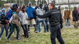 Flüchtlinge am Eurotunnel: Ein einzelner Polizist stellt sich der Menschenmenge entgegen.