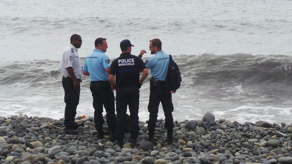 MH370 Koffer Polizei Sicherheitskräfte stehen an dem Strandabschnitt auf der Insel La Réunion, an dem das Wrackteil und der Koffer gefunden wurden
