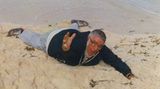 Mann liegt auf dem Bauch am Strand