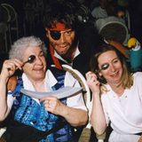 Zwei Damen halten sich einen Löffel vor ihr linkes Auge