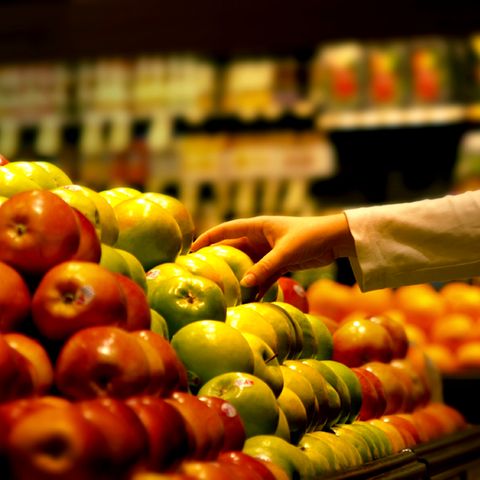 Eine Hand rgeift im Supermarkt zu einem Apfel.