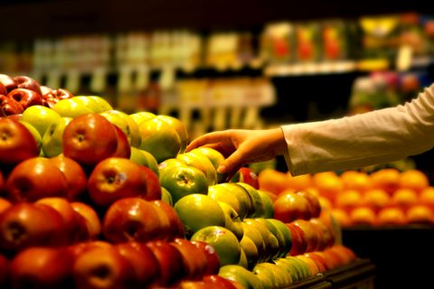 Eine Hand rgeift im Supermarkt zu einem Apfel.