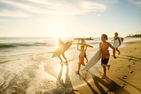 Familie am Strand Eine Familie läuft mit Surfbrettern am Strand entlang.