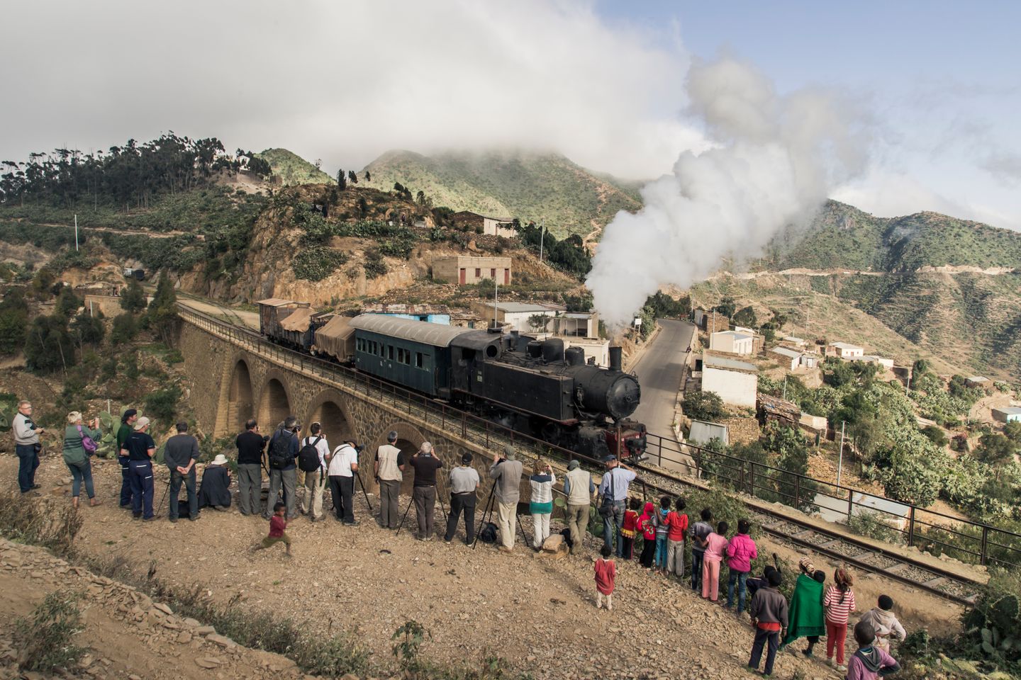 Der Zug bei der Überfahrt der Brücke in Arbaroba, Eritrea am 06.12.2014. Im Vordergrund stehen Teilnehmer der Reisegruppe und fotografieren den Zug.