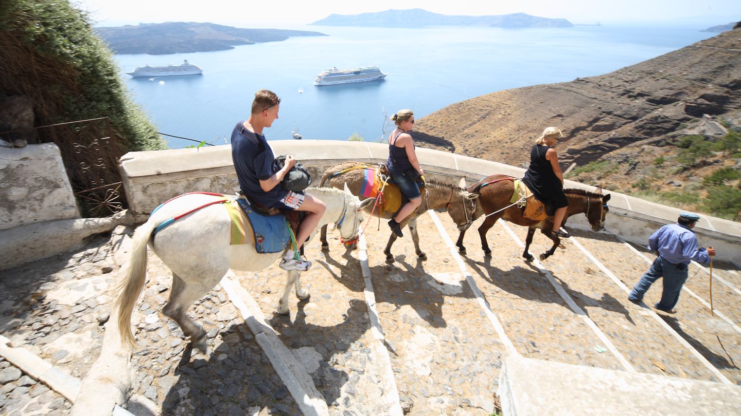 Touristen reiten auf der griechischen Insel Santorin auf Eseln