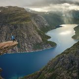 Ein Mensch steht an Ende der Felszunge über dem Abgrund