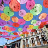 Bunt strahlen Sonnenschirme über der Straße im Himmel