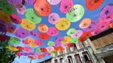 Bunt strahlen Sonnenschirme über der Straße im Himmel