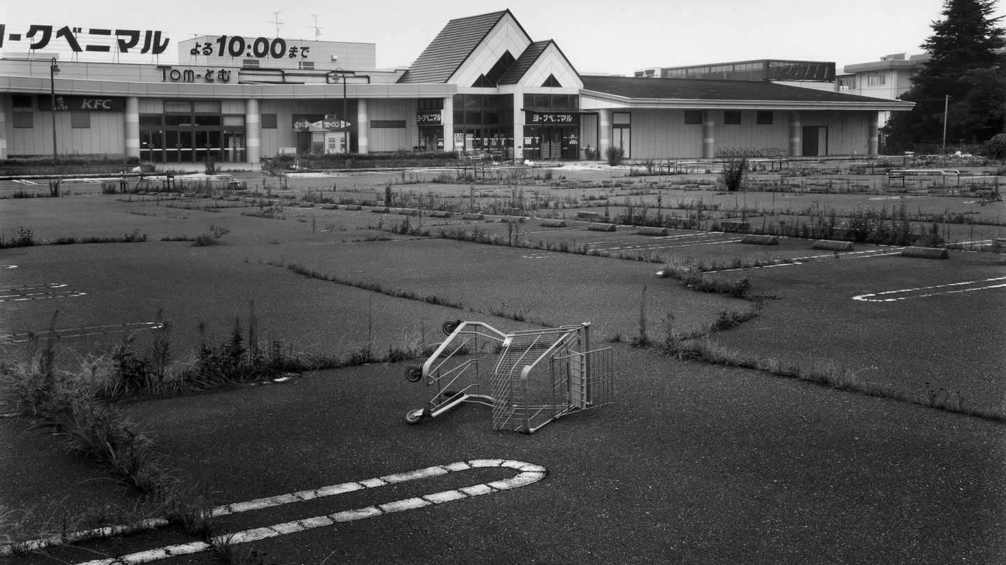 Leben nach Atomkatastrophe: Einst war es der größte Supermarkt in der Region, die heute zum Sperrgebiet gehört. Der große Parkplatz ist verlassen, der Asphalt aufgeplatzt - dazwischen wuchern Gräser. Ein umgekippter Einkaufswagen zeugt vom einstigen Einkaufstrubel, der hier herrschte. Heute ist es still geworden. Einst war es der größte Supermarkt in der Region, die heute zum Sperrgebiet gehört. Der große Parkplatz ist verlassen, der Asphalt aufgeplatzt - dazwischen wuchern Gräser. Ein umgekippter Einkaufswagen zeugt vom einstigen Einkaufstrubel, der hier herrschte. Heute ist es still geworden.