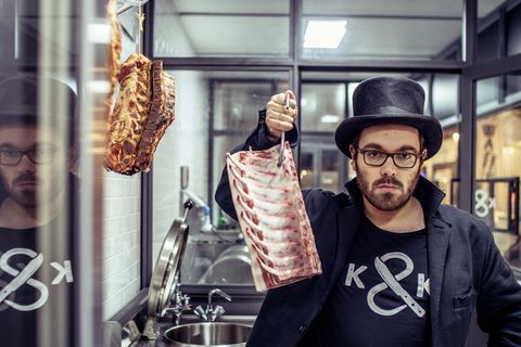 Hendrik Haase steht in seiner Metzgerei "Kumpel & Keule" und hält ein Stück Schweinerippe in die Höhe