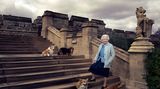 Königin Elisabeth II auf einer Steintreppe 2016 mit vier Hunden