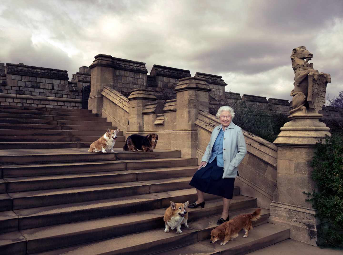 Königin Elisabeth II auf einer Steintreppe 2016 mit vier Hunden