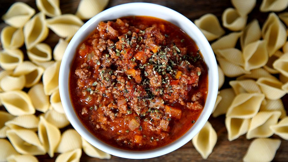 Eine Schale mit Bolognese. Drum herum liegen Nudeln. Eine Schale mit Bolognese. Drum herum liegen Nudeln.