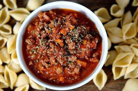 Eine Schale mit Bolognese. Drum herum liegen Nudeln.