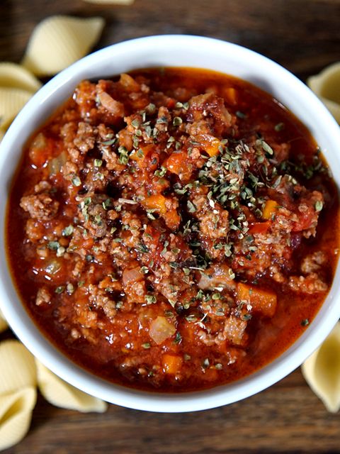 Eine Schale mit Bolognese. Drum herum liegen Nudeln.