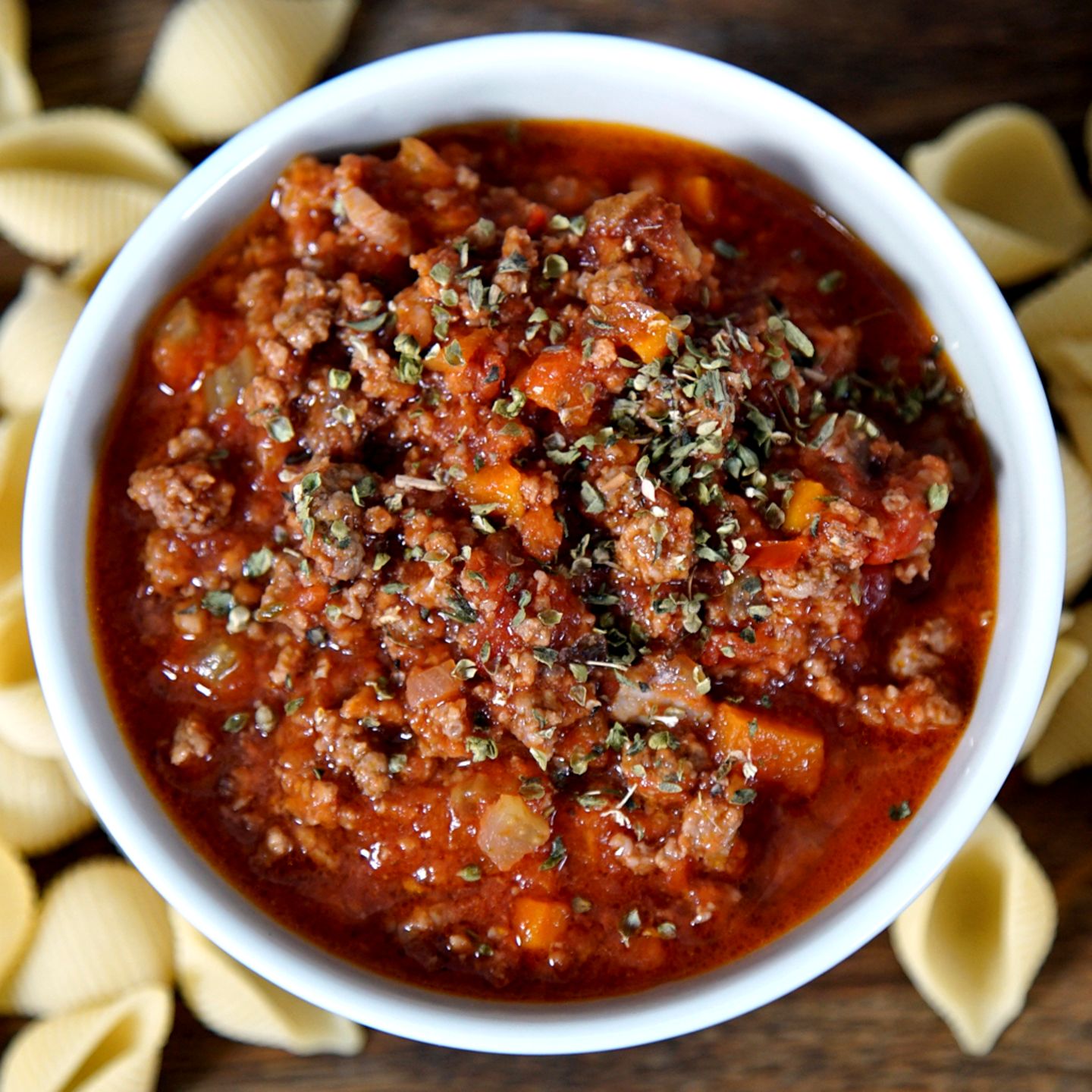 Eine Schale mit Bolognese. Drum herum liegen Nudeln.
