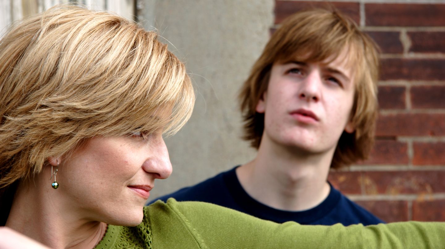 Seitenansicht einer blonden Frau, ein pubertierender Junge starrt in den Himmel