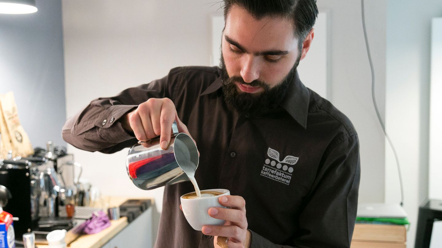 Barista Lino Torke von der Kaffeerösterei Torrefaktum demonstriert, wie man den perfekten Milchschaum mit Herzmotiv hinbekommt