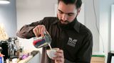 Barista Lino Torke von der Kaffeerösterei Torrefaktum demonstriert, wie man den perfekten Milchschaum mit Herzmotiv hinbekommt