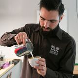 Barista Lino Torke von der Kaffeerösterei Torrefaktum demonstriert, wie man den perfekten Milchschaum mit Herzmotiv hinbekommt