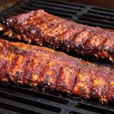 Baby-Back-Ribs  Für 4 Personen  Zubereitungszeit: 15 Minuten  Grillzeit: 2-2 1/4 Stunden  Zubehör: 3 große handvoll Hickoryholz-Chips, Gasgrill mit mindestens 3 Brennern, Räucherbox aus Metall, Sprühflasche mit Wasser      Zutaten:  Für die Würzpaste:    2 EL mittelscharfer Senf    2 EL Worcestersauce    2 TL grobes Meersalz    2 TL Rohrohrzucker    2 TL Chilipulver    1 TL Knoblauchpulver    1 TL frisch gemahlener schwarzer Pfeffer        2 Baby Back Ribs ( Kotelettrippchen; je 1–1 ½ kg)    250 ml Barbecue-­‐Sauce (Fertigprodukt)      Zubereitung:  1. Die Räucherchips mind. 30 Min. wässern.    2. Die Zutaten für die Würzpaste verrühren und die Ribs gleichmäßig damit einreiben; würzen Sie dabei die Fleischseite mehr als die Knochenseite.    3. Vor dem Anzünden des Gasgrills die Chips abtropfen lassen und in die Räucherbox geben. Die Räucherbox unter den Grillrost über einem der Brenner auf einer Seite des Grills stellen. Den Grill für indirekte starke Hitze (230 bis 290 °C) vorbereiten und dabei die Räucherchips in der Box mit erhitzen.  Sobald Rauch entsteht, die Temperatur im Grill so genau wie möglich auf 150 °C absenken.    4. Die Rippen mit den Knochen nach unten auf den Grillrost legen und über indirekter schwacher Hitze bei geschlossenem Deckel 1 Std. grillen, dabei die Temperatur möglichst konstant bei 150 °C halten. Dazu müssen Sie vielleicht immer mal wieder einen der Brenner ausschalten, insbesondere an heißen Tagen. Die Chips sollten etwa 30 Min. lang Rauch abgeben. Wenn sie Feuer fangen, einfach etwas Wasser über die Räucherbox sprühen.  5. Nach 1 Std. Grillzeit die Ribs mit etwas Wasser besprühen und für ein gleichmäßiges Garen auf dem Rost umplatzieren. Nach 1 ½ Std. die Baby Back Ribs auf beiden Seiten mit der Hälfte der Barbecue-Sauce bepinseln. Anschließend mit der Knochenseite nach unten weitere 30–40 Min. über indirekter schwacher Hitze bei geschlossenem Deckel grillen, bis ein Großteil der Knochenenden etwa 6 mm frei liegt. Machen Sie die Garprobe, ob das Fleisch zart genug ist: Wenn Sie die Ribs mit der Knochenseite nach oben an einem Ende mit einer Zange anheben, sollten sie sich in der Mitte so stark biegen, dass das Fleisch einreißt.  6. Die Ribs vom Grill nehmen und kurz vor dem Servieren dünn mit Barbecue-­‐Sauce bestreichen. Die Rippen zwischen den Knochen in einzelne Ribs schneiden und warm servieren.