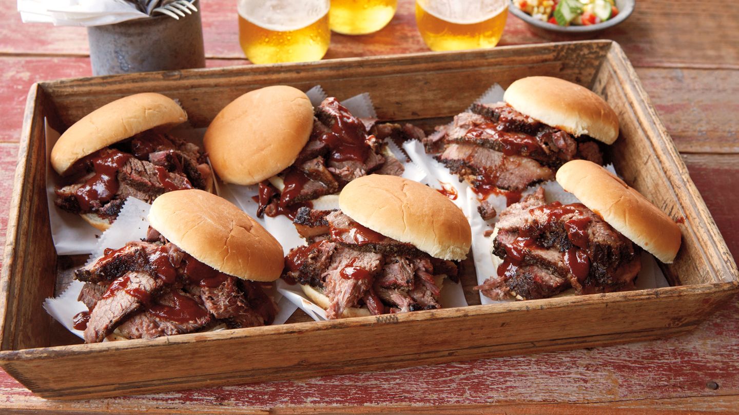Beef Brisket (für Einsteiger)  Die Variante bietet die Möglichkeit, die Rinderbrust am frühen Vormittag zuzuberieten und sie bereits zum Abendessen fertig zu haben. Normalerweise brauchte eine gut 6 kg schwere Rinderbrust bis zu 16 Stunden.        Rezept für Beef Brisket  Für 10 Personen  Zubereitungszeit: 30 Min.  Garzeit: 6-7 Stunden  Ruhezeit: 2-3 Stunden  Zubehör: Räuchergrill (Water Smoker), Sprühflasche mit Wasser, 6-8 große Mesquite-, Eichen- oder Apfelholz-Chunks, digitales Fleischthermometer, extra reissfeste Alufolie, trockene, gut isolierte Kühlbox      Zutaten:  1 ausgelöste Rinderbrust mit Fettauflage (4½–5½ kg Brustspitz, nach US Zuschnitt mit Flat‐ und Point-Stück), nicht pariert    5 EL grobes Meersalz    4 EL frisch gemahlener schwarzer Pfeffer    500ml Barbecue­‐Sauce (nehmen Sie Ihre Lieblingssauce)    10 Burger­‐Brötchen, aufgeschnitten        Zubereitung:  Den Fettdeckel der Rinderbrust mit einem sehr scharfen Messer gleichmäßig bis auf ½cm  bschneiden (auf keinen Fall das Fett ganz wegschneiden). Das Fleisch umdrehen und die dünne Silberhaut entfernen, sodass das grob gemaserte Fleisch darunter sichtbar wird. Harte Fettklumpen auf beiden Seiten der Brust abschneiden.    2. Salz und Pfeffer mischen. Die Rinderbrust gleichmäßig von allen Seiten mit der Würzmischung einreiben. Das Fleisch vor dem Grillen kalt stellen.  3. Den Räuchergrill für indirekte sehr schwache Hitze (etwa 110 °C) vorbereiten.    4. Die Rinderbrust auf beiden Seiten mit Wasser nass sprühen. Die Hälfte der Chunks auf die Glut geben. Sobald Rauch entsteht, die Rinderbrust mit der Fettseite nach unten auf die oberste Ebene in den Räuchergrill legen und den Deckel schließen. Das Fleisch bei indirekter sehr schwacher Hitze etwa 4 Std. räuchern, bis sich eine schön dunkle Kruste gebildet hat, dabei nach 1 Std. die restlichen Holzstücke auf die Glut geben. Die tiefdunkle Farbe der Kruste ist ein sicheres Anzeichen dafür, dass das Fleisch jetzt »versiegelt« ist, d.h. kaum mehr Raucharomen aufnimmt. Für Sie ist das der Zeitpunkt, an dem Sie das Fleisch in Alufolie einwickeln müssen. Die Farbe der Kruste ist dafür der wichtigste Hinweis, sie sollten jedoch zusätzlich mit dem Fleischthermometer die Kerntemperatur messen, die an der dicksten Stelle der Brust 65–70 °C betragen sollte.    5. Die Rinderbrust vom Grill nehmen und auf beiden Seiten erneut mit Wasser besprühen. Anschließend mit der Fettseite nach unten dicht in eine doppelte oder dreifache Lage extra reißfeste Alufolie einwickeln.    6. Die eingepackte Rinderbrust mit der Fettseite nach unten zurück auf die oberste Ebene des Räuchergrills legen. Über indirekter sehr schwacher Hitze und bei geschlossenem Deckel 2–3 Std. weitergaren, bis sich das in Folie gewickelte Fleisch auf Fingerdruck weich wie ein Riesen-Marshmallow anfühlt und die Kerntemperatur zwischen 90 und 95 °C liegt (die Mürbheit des Fleisches zeigt den richtigen Gargrad jedoch besser an als die Kerntemperatur). Bitte bedenken Sie dabei, dass die Garzeit auch von der verwendeten Rinderrasse und anderen Eigenschaften des Fleisches abhängt.     7. Die Rinderbrust in der Folie vom Grill nehmen und in eine trockene, gut isolierte Kühlbox legen.  Die Kühlbox schließen und das Fleisch etwa 2–3 Std. nachziehen lassen.  8. Danach die Rinderbrust auf einem Schneidbrett vorsichtig aus der Folie wickeln und den kostbaren Fleischsaft in der Folie auffangen.  9. Die Barbecue-Sauce bei mittlerer Stufe auf dem Herd etwa 5 Min. erwärmen. Die Rinderbrust quer zur Faser in dünne Scheiben schneiden und warm mit der Sauce servieren. Nach Belieben den aufgefangenen Fleischsaft vorher noch in die Sauce rühren. Sollte das Fleisch des Flat-Stücks etwas trocken sein, zerpflücken Sie es grob und mischen Sie es nach Geschmack mit Barbecue-­Sauce. Anschließend warm in den Brötchen servieren.