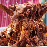 Pulled Pork Kansas-City-Style  Für 10-12 Personen  Zubereitungszeit: 30 Min.    Grillzeit: etwa 5,5 Stunden    Ruhezeit: 1 Stunde    Zubehör: Holzkohlegrill, 4 große Apfel-, Kirsch- oder HIckoryholz-Chunks, große Einweg-Aluschale, Sprühflasche mit Wasser, extra reißfeste Alufolie, digitales Fleischthermometer      Zutaten:  FÜR DIE WÜRZMISCHUNG    110 g Rohrohrzucker    4 EL geräuchertes Paprikapulver    4 TL grobes Meersalz    2½ TL Chilipulver    2½ TL Knoblauchpulver    2½ TL Zwiebelpulver    1 ½ TL grob gemahlener schwarzer Pfeffer    ½–1 TL Cayennepfeffer        2 kg ausgelöster Schweineschulterbraten (Boston-Butt-Zuschnitt, d. h. mit Nackenstück), überschüssiges Fett und Silberhaut entfernt        FÜR DIE SAUCE    3 Scheiben Frühstücksspeck    ½ mittelgroße Zwiebel, fein gewürfelt    3 Knoblauchzehen, fein gehackt    120 ml Ketchup    120 ml heller Zuckersirup    120 ml Apfelessig    4 EL Tomatenmark    4 EL Chilipulver    2 EL Rohrohrzucker    1 EL Zuckerrohrmelasse    1 EL Worcestersauce    1 TL Selleriesalz    ½ TL grobes Meersalz        Zubereitung:  1. Die Zutaten für die Würzmischung vermengen und den Braten damit rundherum bestreuen. Vor dem Grillen bei Raumtemperatur 30 Min. ruhen lassen.    2. Den Grill für indirekte sehr schwache Hitze (110–120 °C) mit der Minion-Ring- Methode vorbereiten (eine Anleitung finden Sie auf Seite 76). Sobald die Temperatur im Grill 110 °C erreicht hat, das Fleisch mit der Fettseite nach unten auf den Grillrost legen und über indirekter sehr schwacher Hitze bei geschlossenem Deckel 4 Std. grillen, dabei mithilfe der oberen Lüftungsschieber die Temperatur so konstant wie möglich bei 110 °C halten. Den Braten nach 1 Std. Garzeit mit etwas Wasser besprühen und dies dann jede Stunde wiederholen.  3. In der Zwischenzeit die Sauce zubereiten. Den Speck in einem mittelgroßen Topf mit schwerem Boden auf mittlerer Stufe braten, bis das meiste Fett ausgelassen ist. Mit einem Schaumlöffel herausheben und gleich an Ort und Stelle verspeisen oder für eine andere Verwendung aufbewahren. Das ausgelassene Fett im Topf bis auf 2– 3 EL abgießen, dann die Zwiebel im heißen Speckfett in 3–4 Min. glasig dünsten, dabei ab und zu umrühren. Den Knoblauch unter gelegentlichem Rühren 1 Min. mitdünsten. Die übrigen Zutaten für die Sauce einrühren und auf mittlerer Stufe 10– 15 Min. köcheln lassen, dabei ab und zu umrühren. Vom Herd nehmen und abkühlen lassen. Die Sauce im Mixer glatt pürieren und anschließend aufteilen: Eine Hälfte ist zum Befeuchten des Bratens, bevor er in Folie gewickelt wird. Die andere Hälfte wird später unter das Pulled Pork gemischt.  4. Nach 4 Std. Garzeit sollte der Braten eine Kerntemperatur von 70 °C haben, andern-falls muss er noch weitergaren. Das Fleisch vom Grill nehmen und den Deckel sofort wieder schließen.    5. Auf einer großen Arbeitsfläche zwei 1 m lange Bögen extra reißfeste Alufolie kreuzförmig übereinanderlegen. Den Braten mit der Fettseite nach oben in die Folienmitte legen und oben und an den Seiten dünn mit Sauce bestreichen. Zuerst die Enden des inneren Folienbogens über dem Braten zusammenfalten, dann den Braten fest in den äußeren Folienbogen einwickeln, damit kein Dampf austreten kann. Zurück auf den Grillrost legen und über indirekter sehr schwacher Hitze bei geschlossenem Deckel so lange weitergrillen, bis der Braten nach etwa 1 ½ Std. eine Kerntemperatur von 88–90 °C hat. Vom Grill nehmen und 1 Std. in der Alufolie nachziehen lassen.    6. Den Braten auswickeln, etwas abkühlen lassen, dann das Fleisch zerpflücken. Größere Fettstücke und Sehnen entfernen und wegwerfen. Das Pulled Pork mit Sauce mischen und sofort servieren.