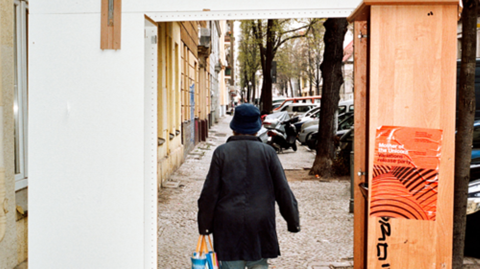 Eine Frau geht mit einer Plastiktüte an einer Hausfassade entlang. Franziska Giffey spricht über das Regieren in Neukölln.