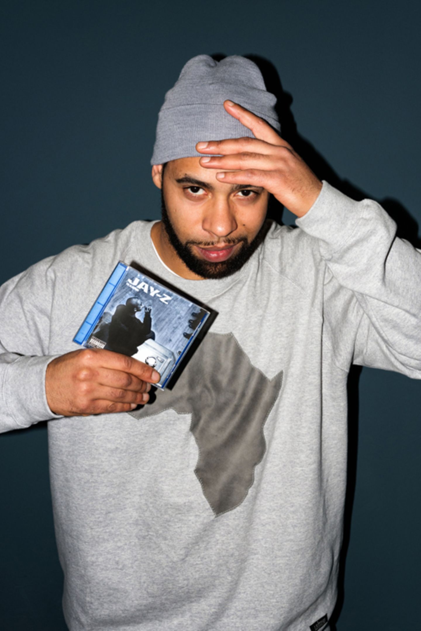 Megaloh hält das Album »The Blueprint« von Jay-Z in der Hand