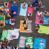 An einem Strand in Sorrento, Italien, liegen viele Menschen dicht gedrängt auf ihren Handtüchern nebeneinander