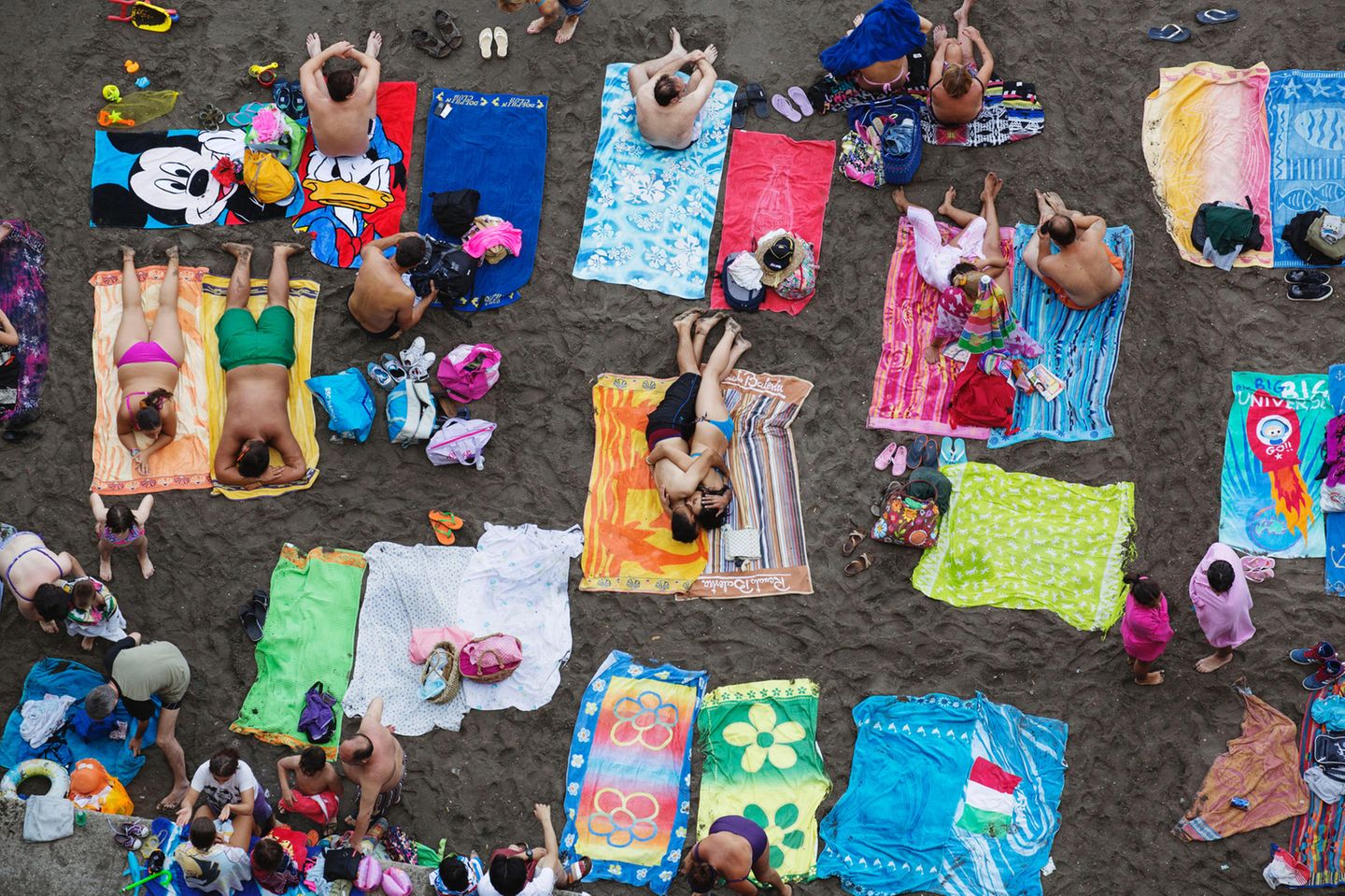 An einem Strand in Sorrento, Italien, liegen viele Menschen dicht gedrängt auf ihren Handtüchern nebeneinander