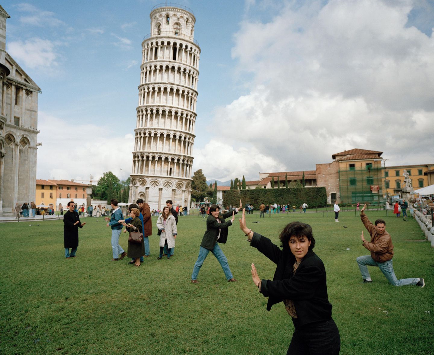 Am schiefen Turm von Pisa posieren Menschen so davor, dass es aus dem richtigen Blickwinkel scheint, sie würden den Turm stützen