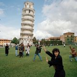 Am schiefen Turm von Pisa posieren Menschen so davor, dass es aus dem richtigen Blickwinkel scheint, sie würden den Turm stützen