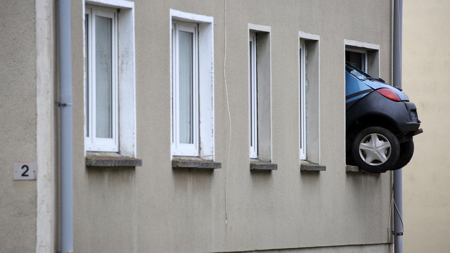 Das Heck eines Kleinwagens ragt aus dem Fenster eines Mehrfamilienhauses in Kummer