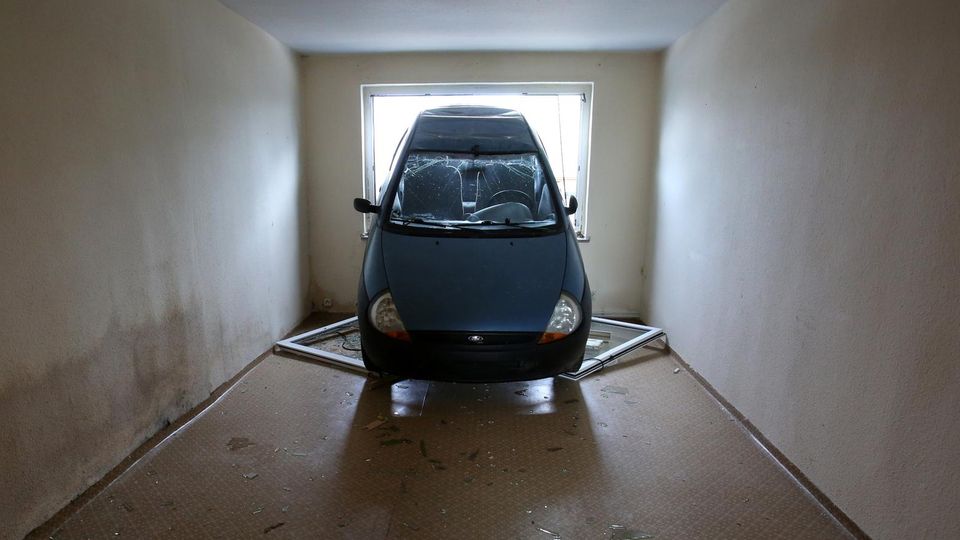 Das Heck eines Kleinwagens ragt aus dem Fenster eines Mehrfamilienhauses in Kummer