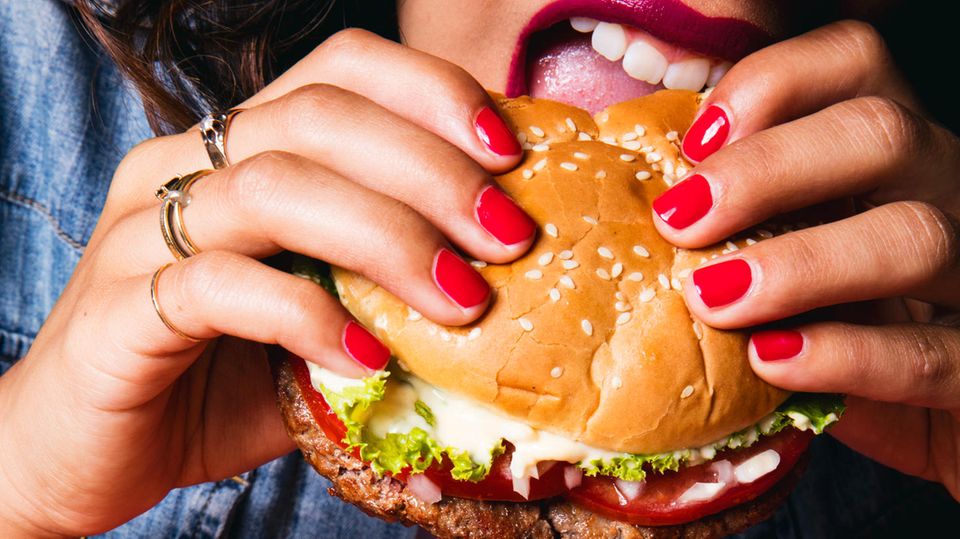 Eine Frau beißt in den Impossible Burger.