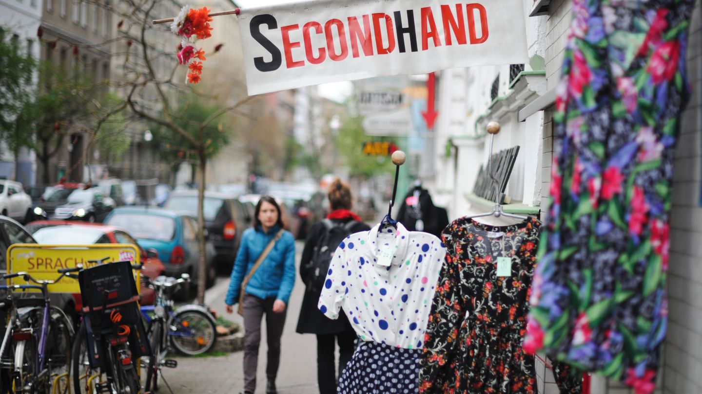 Konsum-Entscheidungen Eine Frau geht an einem Second-Hand-Shop vorbei.