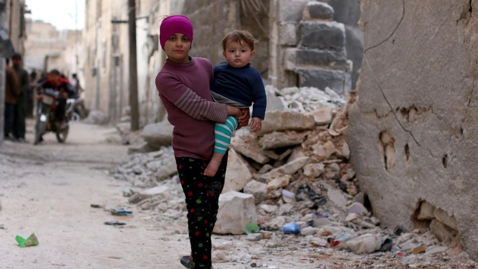 Ein Mädchen in Syrien trägt ihren kleinen Bruder auf dem Arm