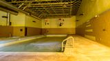 Das städtische Schwimmbad ist mit einer dicken Kruste aus Dreck und Staub bedeckt. Im Pool befindet sich noch Wasser.