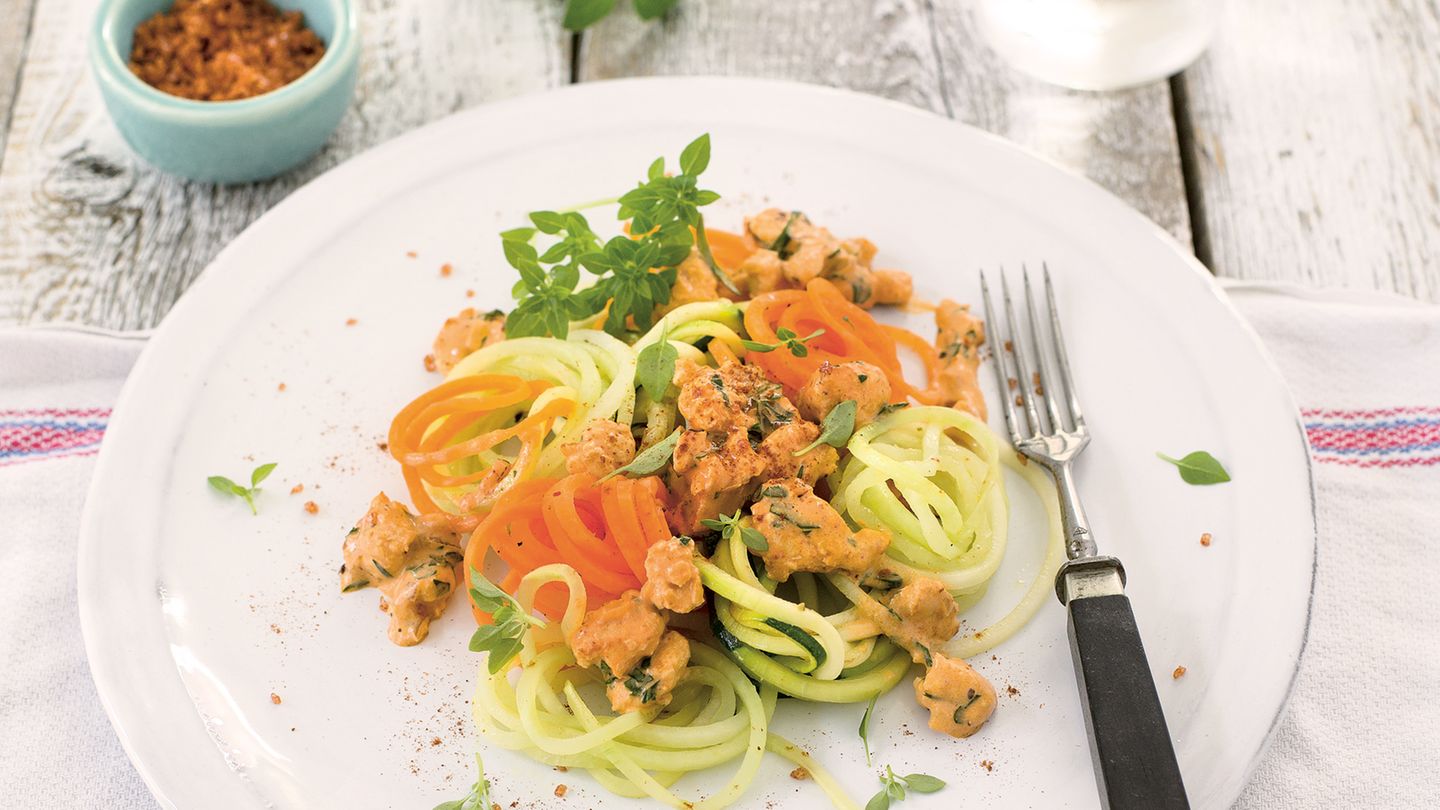 Gemüsespaghetti mit Hähnchen-Bolognese  Zutaten:  400 g Hähnchenbrust, 1 Zwiebel, 1 Knoblauchzehe, 2 EL Olivenöl, 2 EL Tomatenmark, 100 ml Gemüsebrühe, 50 g süße Sahne, Meersalz, frisch gemahlener schwarzer Pfeffer, 3 Stängel Oregano, 2 Karotten, 1 Kohlrabi, 2 dünne Zucchini, 1 Bund Petersilie, Saft von ½ Zitrone, Chilisalz (alternativ Cayennepfeffer und Salz), 2 Stängel Basilikum      Zubereitung:  1. Für die Bolognese die Hähnchenbrust grob würfeln und durch die grobe Scheibe des Fleischwolfs lassen. Zwiebel und Knoblauch abziehen und würfeln. 1 EL Olivenöl in einem Bräter erhitzen, das Fleisch darin kurz scharf anbraten. Die Zwiebel- und Knoblauchwürfel zugeben und anschwitzen. Das Tomatenmark unter Rühren anrösten. Mit Gemüsebrühe und Sahne aufgießen, Salz und Pfeffer zugeben. Den Oregano abbrausen, trocken schütteln und zugeben. Die Sauce bei mittlerer Temperatur offen 15 Minuten köcheln lassen.        2. Inzwischen das Gemüse waschen, die Karotten und den Kohlrabi schälen.  Mit Hilfe eines Spiralschneiders das Gemüse in lange dünne Spaghetti schneiden. Die Petersilie abbrausen, trocken schütteln und hacken.        3. Das restliche Olivenöl in einer Pfanne erhitzen, die Gemüsespaghet ti darin etwa 2 Minuten anschwitzen. Mit Salz und Pfeffer bestreuen. Oregano aus der Sauce nehmen und die Sauce mit Zitronensaft und Chilisalz abschmecken, die Petersilie unterrühren.        4. Die Gemüsespaghetti mit der Sauce anrichten. Basilikum waschen, trocken schütteln und die Blätter darüber streuen.