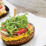 Weißer Burger  Zutaten:  250 g Hähnchenbrust, 1 Zwiebel, ½ TL Paprikapulver, ½ TL zerstoßener Szechuanpfeffer, 1 EL Bio-Tamari (glutenfreie Sojasauce), Meersalz, frisch gemahlener schwarzer Pfeffer, 2 EL Olivenöl, 4 Portobello-Pilze, 1 Handvoll Rucola, 1 Strauchtomate, 1–2 EL Tofunese (oder Mayonnaise aus dem Glas), 2 EL Schnittlauchröllchen, 1 EL Senf      Zubereitung:  1. Die Hähnchenbrust in dicke Streifen schneiden und durch die grobe Scheibe des Fleischwolfs drehen. Die Zwiebel abziehen und würfeln.  Zwiebel, Paprikapulver, Szechuanpfeffer und Tamari zum Fleisch geben.  Salz und Pfeffer zugeben. Alles kräftig verrühren, zwei flache Pattys daraus formen und mit etwas Olivenöl bestreichen.        2. Eine Grillpfanne aufheizen. Die Stiele der Portobello-Pilze abschneiden.  Die Pilze mit Salz und Pfeffer bestreuen und mit Olivenöl bestreichen. Pilze und Pattys in der Pfanne von beiden Seiten 2–3 Minuten kräftig anbraten.  Die Temperatur auf ein Drittel herunterschalten und beides weitere 5 Minuten braten lassen.        3. Den Rucola waschen und trocken schleudern. Die Tomate waschen, Blütenansatz entfernen und die Tomate in dünne Scheiben schneiden.  Die Tofunese mit dem Schnittlauch verrühren.        4. Zwei Portobello-Pilze mit der runden Seite nach unten auf einen Teller setzen. Mit dem Senf bestreichen. Die Hähnchenburger darauf legen, 1 TL Tofunese daraufgeben und mit Tomatenscheiben und Rucola bedecken.  Zuletzt nochmals einige Tupfen Tofunese darauf verteilen und mit den anderen beiden Pilzen bedecken. Mit einem Holzspieß feststecken.