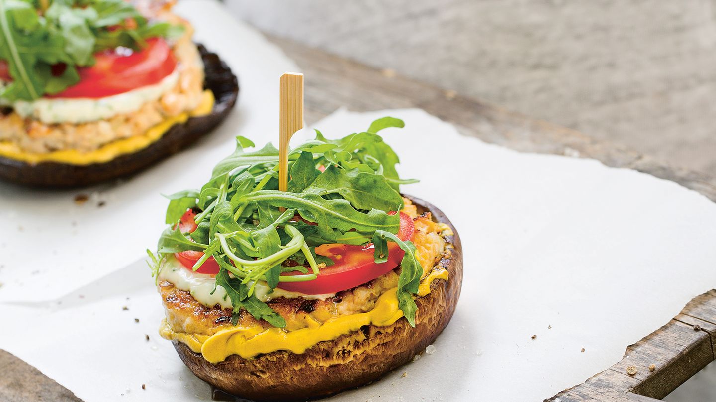 Weißer Burger  Zutaten:  250 g Hähnchenbrust, 1 Zwiebel, ½ TL Paprikapulver, ½ TL zerstoßener Szechuanpfeffer, 1 EL Bio-Tamari (glutenfreie Sojasauce), Meersalz, frisch gemahlener schwarzer Pfeffer, 2 EL Olivenöl, 4 Portobello-Pilze, 1 Handvoll Rucola, 1 Strauchtomate, 1–2 EL Tofunese (oder Mayonnaise aus dem Glas), 2 EL Schnittlauchröllchen, 1 EL Senf      Zubereitung:  1. Die Hähnchenbrust in dicke Streifen schneiden und durch die grobe Scheibe des Fleischwolfs drehen. Die Zwiebel abziehen und würfeln.  Zwiebel, Paprikapulver, Szechuanpfeffer und Tamari zum Fleisch geben.  Salz und Pfeffer zugeben. Alles kräftig verrühren, zwei flache Pattys daraus formen und mit etwas Olivenöl bestreichen.        2. Eine Grillpfanne aufheizen. Die Stiele der Portobello-Pilze abschneiden.  Die Pilze mit Salz und Pfeffer bestreuen und mit Olivenöl bestreichen. Pilze und Pattys in der Pfanne von beiden Seiten 2–3 Minuten kräftig anbraten.  Die Temperatur auf ein Drittel herunterschalten und beides weitere 5 Minuten braten lassen.        3. Den Rucola waschen und trocken schleudern. Die Tomate waschen, Blütenansatz entfernen und die Tomate in dünne Scheiben schneiden.  Die Tofunese mit dem Schnittlauch verrühren.        4. Zwei Portobello-Pilze mit der runden Seite nach unten auf einen Teller setzen. Mit dem Senf bestreichen. Die Hähnchenburger darauf legen, 1 TL Tofunese daraufgeben und mit Tomatenscheiben und Rucola bedecken.  Zuletzt nochmals einige Tupfen Tofunese darauf verteilen und mit den anderen beiden Pilzen bedecken. Mit einem Holzspieß feststecken.