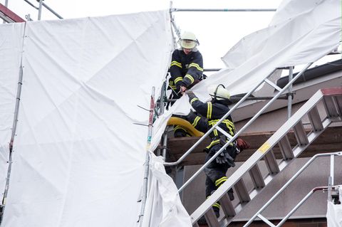 Feuerwehrleute sichern in Hamburg an einem Mehrfamilienhaus Planen an einem Gerüst, die sich durch starken Sturm gelöst haben