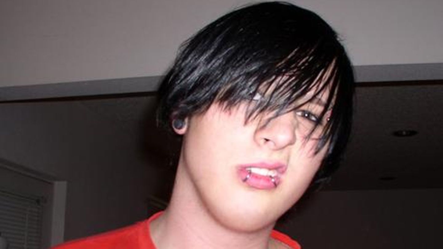 Emo-Kid mit langen, schwarzen Haaren und Piercings