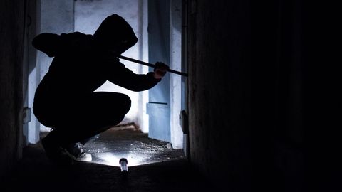 Ein fiktiver Einbrecher versucht mit einem Brecheisen eine Tür aufzuhebeln. Einbruchschutz wird nun staatlich stärker gefördert.
