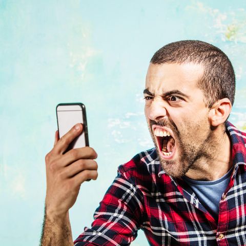 Ein Mann schaut wütend sein iPhone an