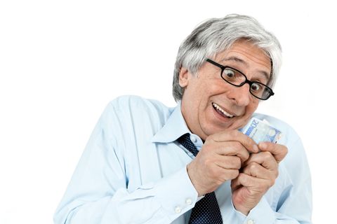 Ein Manns schaut freudig auf einen Geldschein