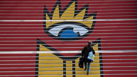 Eine Frau steigt eine Treppe hoch, auf der das Logo der Leipziger Buchmesse zu sehen ist: Ein geöffnetes Buch unter einem Auge.