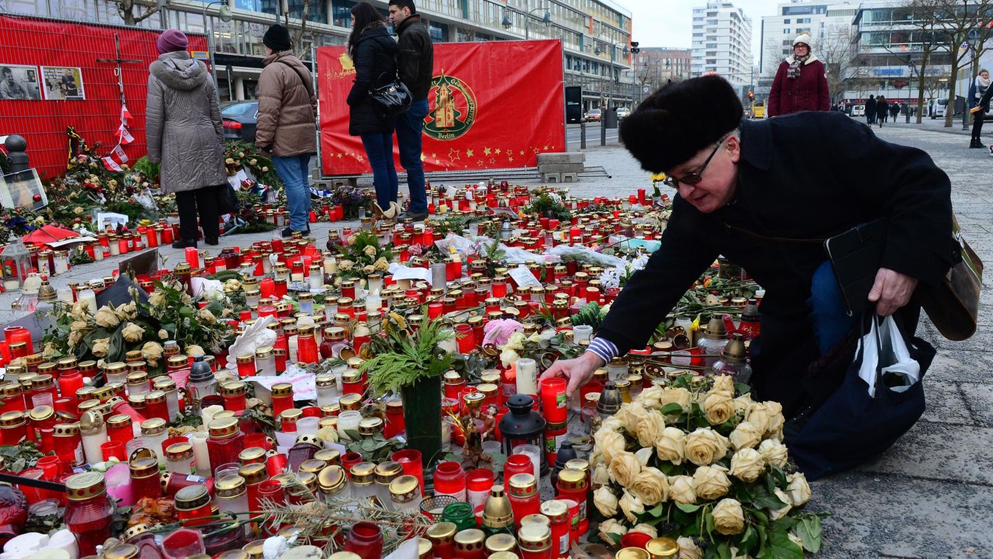 Nach dem Anschlag in Berlin stellt ein Mann eine Kerze auf den Weihnachtsmarkt am Breitscheidplatz